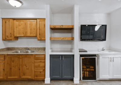 A custom home builder in Southern Utah Valley creates elegant kitchens with wood cabinets and a touch of entertainment through the inclusion of a TV.