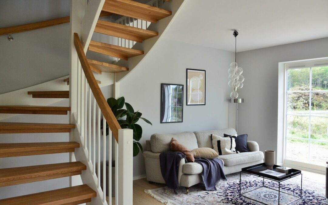 A custom-built living room in Southern Utah Valley featuring a stunning wooden staircase and a comfortable couch.