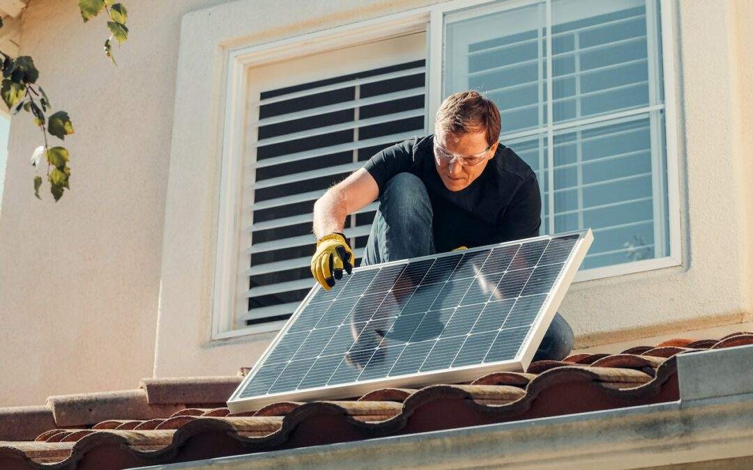 A man installing solar panels on the roof of a custom home in Southern Utah Valley.