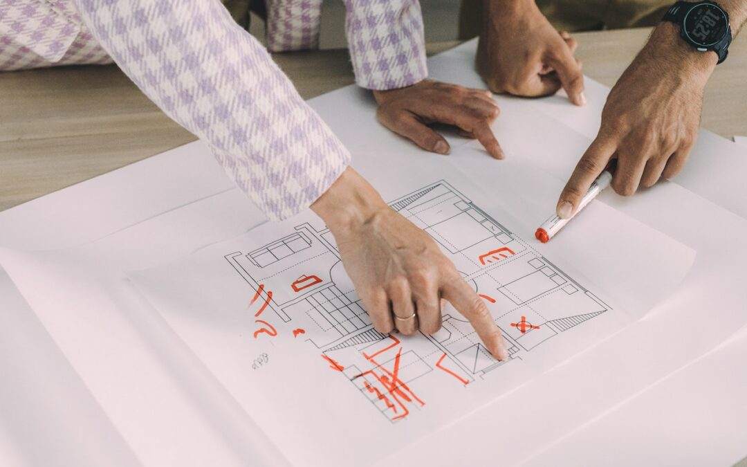 Two people, including a Custom Home Builder, pointing at a drawing of a house plan in Southern Utah Valley.