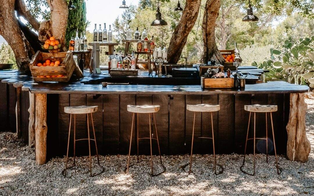 An outdoor bar with stools under a tree, built by a Custom Home Builder in Southern Utah Valley.